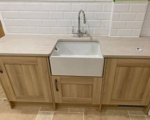 Wooden kitchen cabinets that have had new cream composite worktops installed.