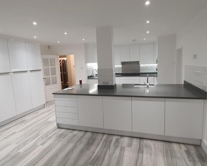 New contemporary kitchen fitted in Southampton featuring grey laminate flooring, white cabinets and cupboards, white wall tiles and grey worktops.